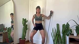 An inked girl warms up with rubber bands for her yoga fitness routine.
