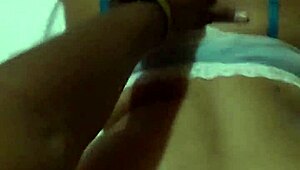 Beautiful cute woman perches on bed edge in white bra showing off huge ass against blue sky.